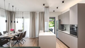 Une cuisine moderne dotée d’un îlot central, d’appareils électroménagers en acier inoxydable et d’un coin repas avec une table dressée pour quatre personnes.