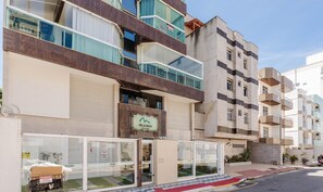 Un immeuble résidentiel à plusieurs étages, doté de balcons, d’un garage et d’une entrée sécurisée par un portail.