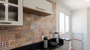 Una cocina con baldosas estampadas, un ventanal y una encimera con un hervidor y una licuadora.
