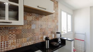 A kitchen with patterned tiles, a window, and a countertop with a kettle and a blender.