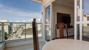 A balcony with a view of a city street, a wooden chair, and a table.