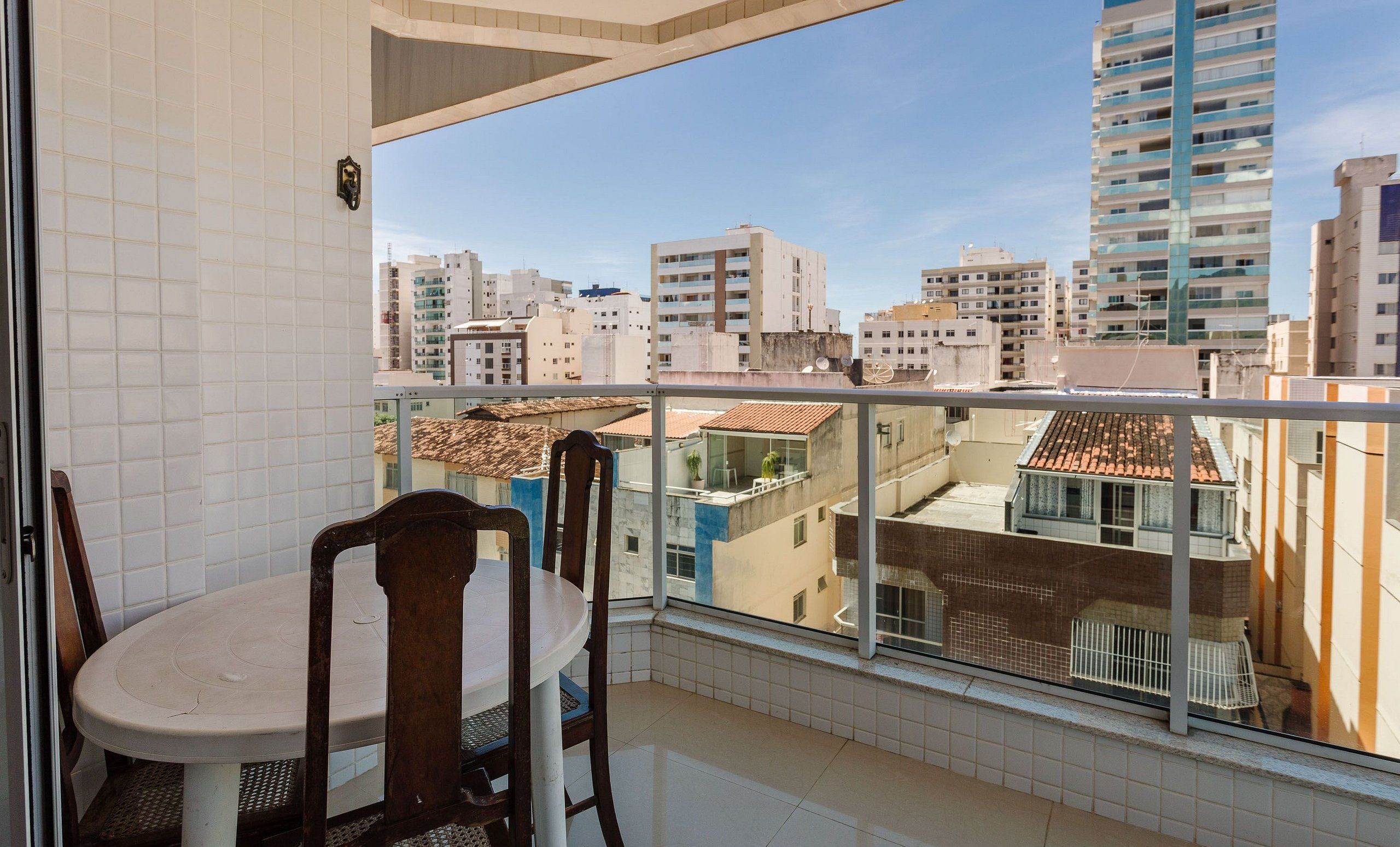 A balcony with a table and chairs, offering a view of a cityscape with various buildings.