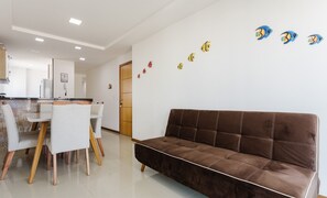 A modern living room with a brown sofa, a dining area with a table and chairs, and a kitchen in the background. - Beautiful apt Just 400m From Praia do Morro Cve402 (Guarapari)
