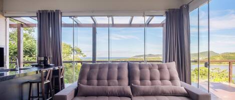 Una sala de estar moderna con un ventanal grande, un sofá y una zona de bar.