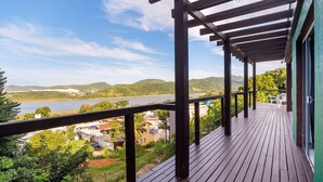 Une terrasse en bois offrant une vue sur un lac et des collines.