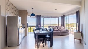 Una sala moderna con comedor, un sofá y un ventanal que ofrece vistas al exterior.