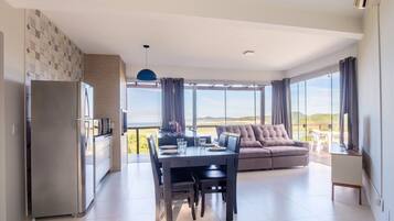 Uma sala de estar moderna com área de jantar, sofá e uma janela ampla com vista para o exterior.