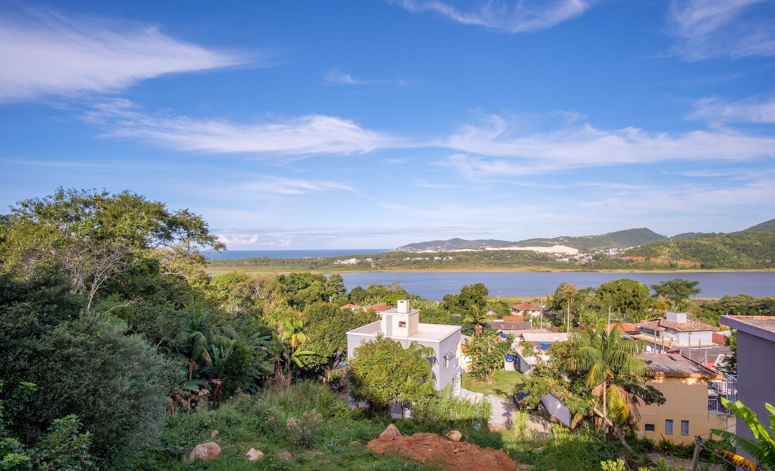 Uma área residencial costeira com casas cercadas por vegetação exuberante e vista para o mar.