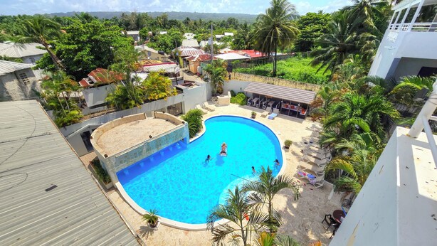 A swimming pool surrounded by palm trees and a lounge area with sun loungers. - 3 BR Penthouse Center Cabarete (Cabarete)