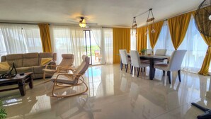 A spacious living area with a sofa, lounge chairs, a dining table with chairs, and a ceiling fan. - 3 BR Penthouse Center Cabarete (Cabarete)