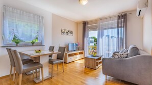 A modern living room with a dining area, a sofa, and a TV.