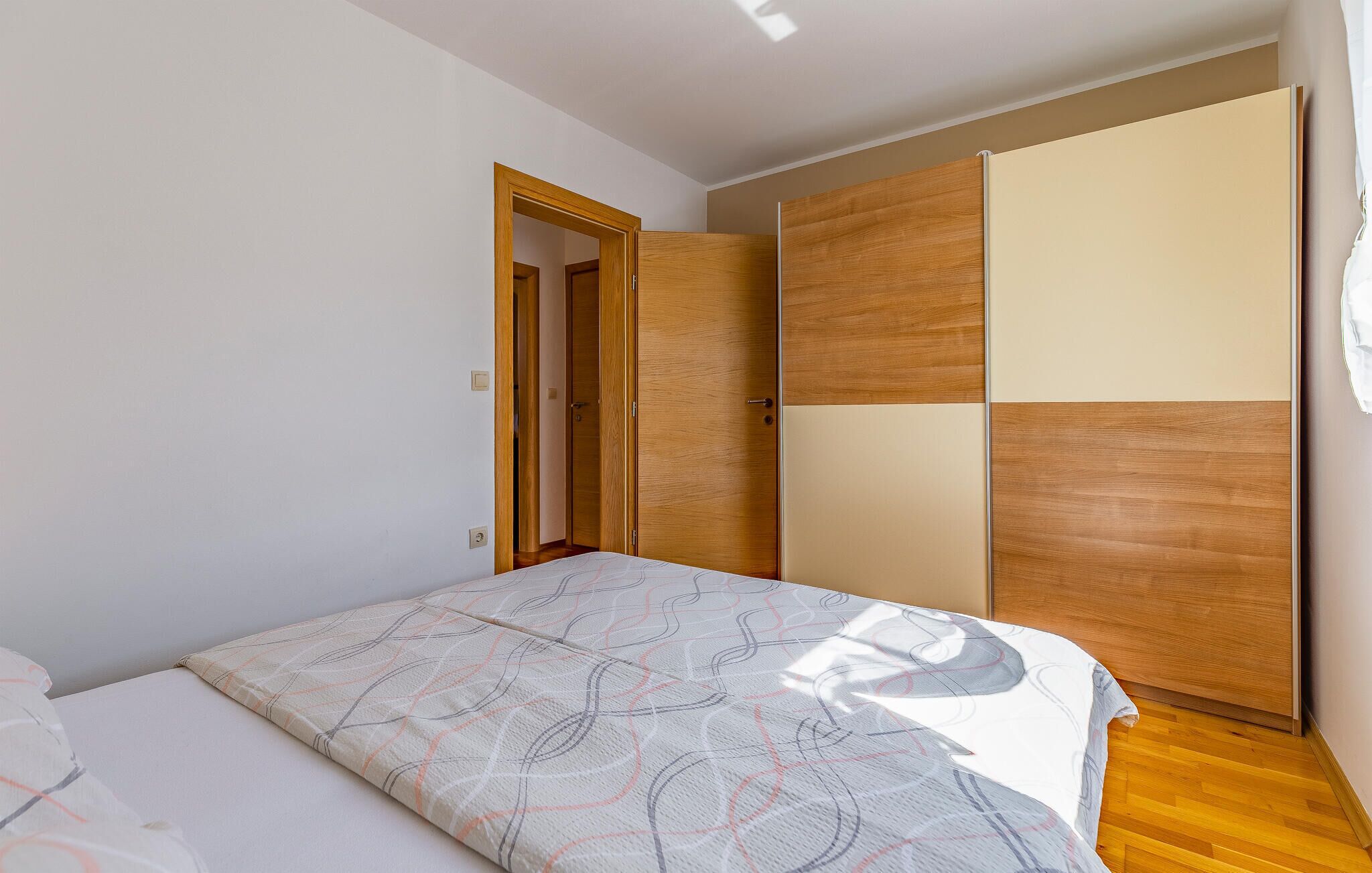 Une chambre à coucher comprenant un lit, une armoire et une porte donnant sur une autre pièce.