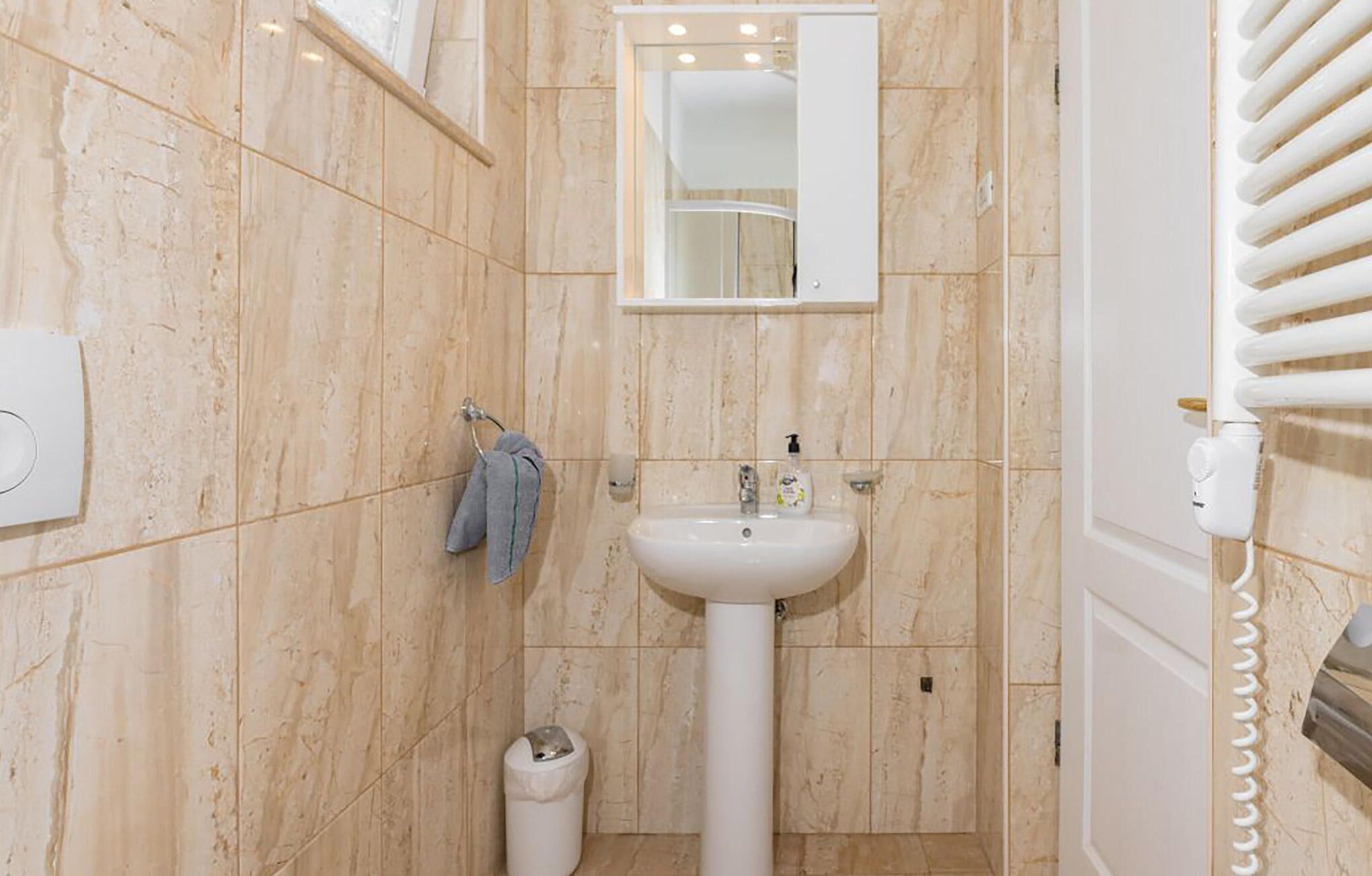 A bathroom with a white pedestal sink, a mirror above it, and a towel hanging on a rack.