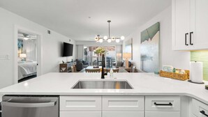 A modern kitchen with a central island, stainless steel sink, and white cabinetry.