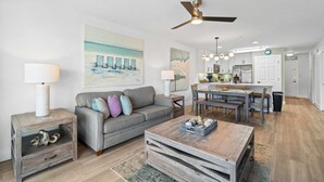 A modern living room with a grey sofa, wooden coffee table, and a ceiling fan.