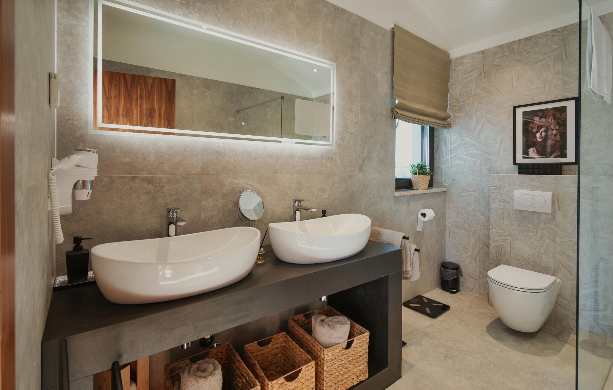 Een moderne badkamer met twee grote wastafels, een spiegel, een douche en een toilet.