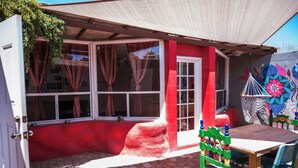 A red and white building with a covered patio area, a table, and colorful chairs.