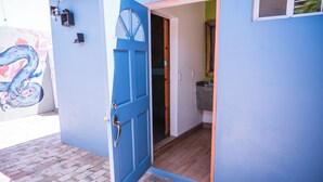 A blue door leading into a room with a wooden floor and a small window.