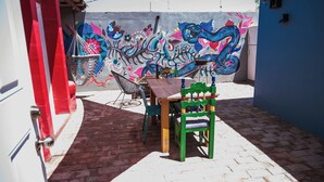 A patio with a table and chairs, a hammock, and a colorful mural on the wall.