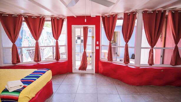 A room with a bed, a ceiling fan, and red curtains.