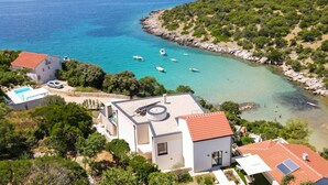 En fastighet vid kusten med en swimmingpool, en brygga och utsikt över havet.
