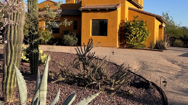 Una casa de dos pisos con fachada de estuco amarillo y techo de tejas marrones.