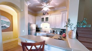 Una cocina con una isla central, electrodomésticos de acero inoxidable y un ventilador de techo.