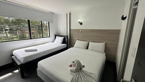 A hotel room with two beds, a large window, a wall-mounted light, and a door with a handle. - Hotel Latin Boutique (Bogotá)