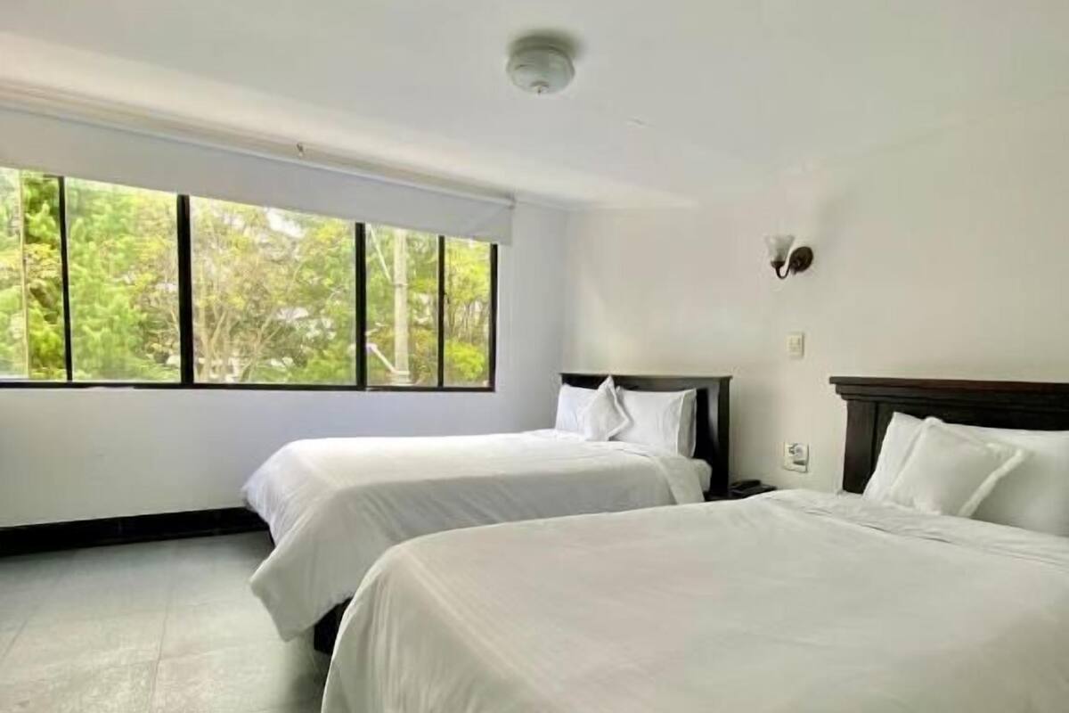 Ein Hotelzimmer mit zwei Betten, einem großen Fenster und einer Deckenleuchte.