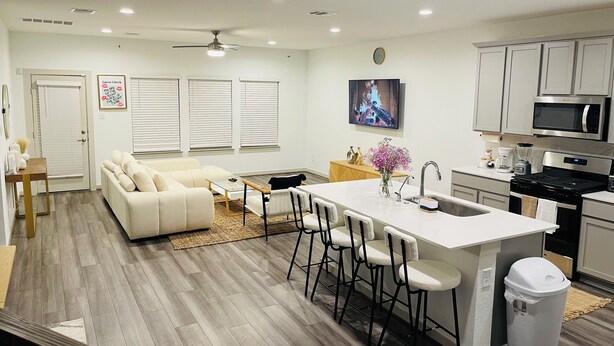 A modern kitchen with a central island, bar stools, a microwave, and a stove. - Charming Elegant Room (Richmond)