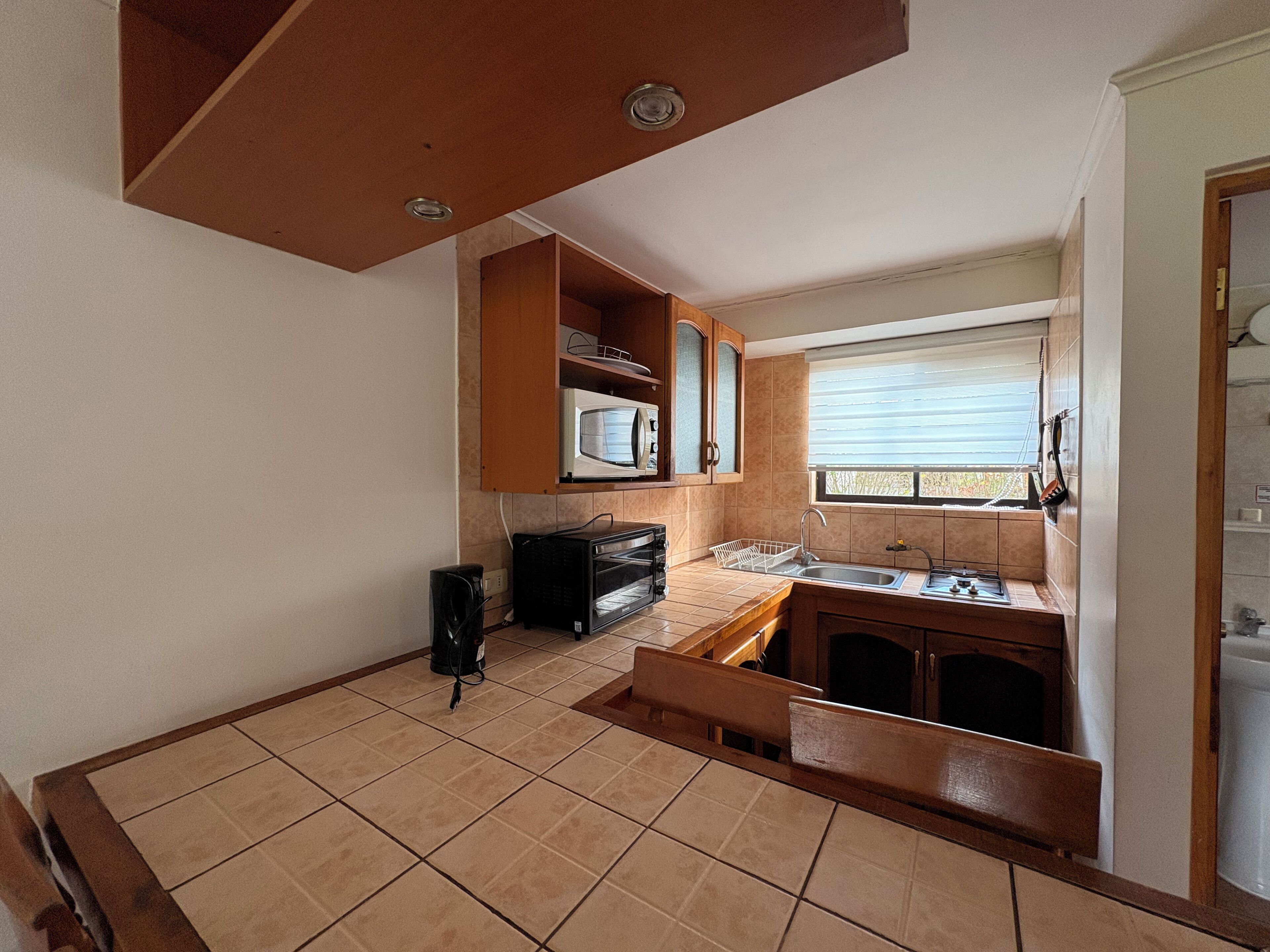 A compact kitchen with a microwave, toaster, and sink.