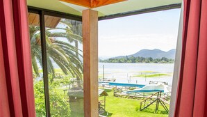 A corner room with a wooden bench, a view of a lake, and a wooden ceiling. - Cabañas Villa Alejandra (Las Cabras)