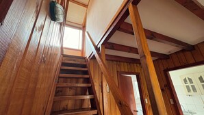 A wooden staircase with a view of a kitchen area. - Cabañas Villa Alejandra (Las Cabras)