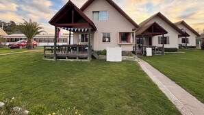 A row of cabins with a covered porch and a grassy lawn. - Cabañas Villa Alejandra (Las Cabras)