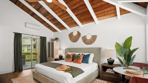Un dormitorio con una cama grande, una mesita de noche, una silla, una mesa de comedor y vistas al exterior.