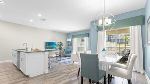 A spacious living area with a kitchen, dining table, and seating. - Champions Gate Resort Home with Pool (Four Corners)
