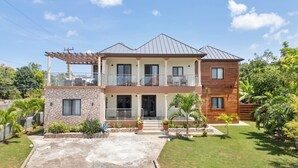 Una casa a due piani con un balcone, un garage e un prato curato.