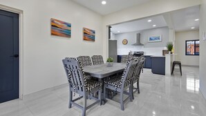 Una cucina moderna con mobili bianchi, un frigorifero in acciaio inossidabile e una sveglia appesa al muro.