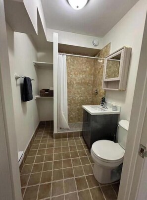 A small bathroom with a shower, toilet, and sink.