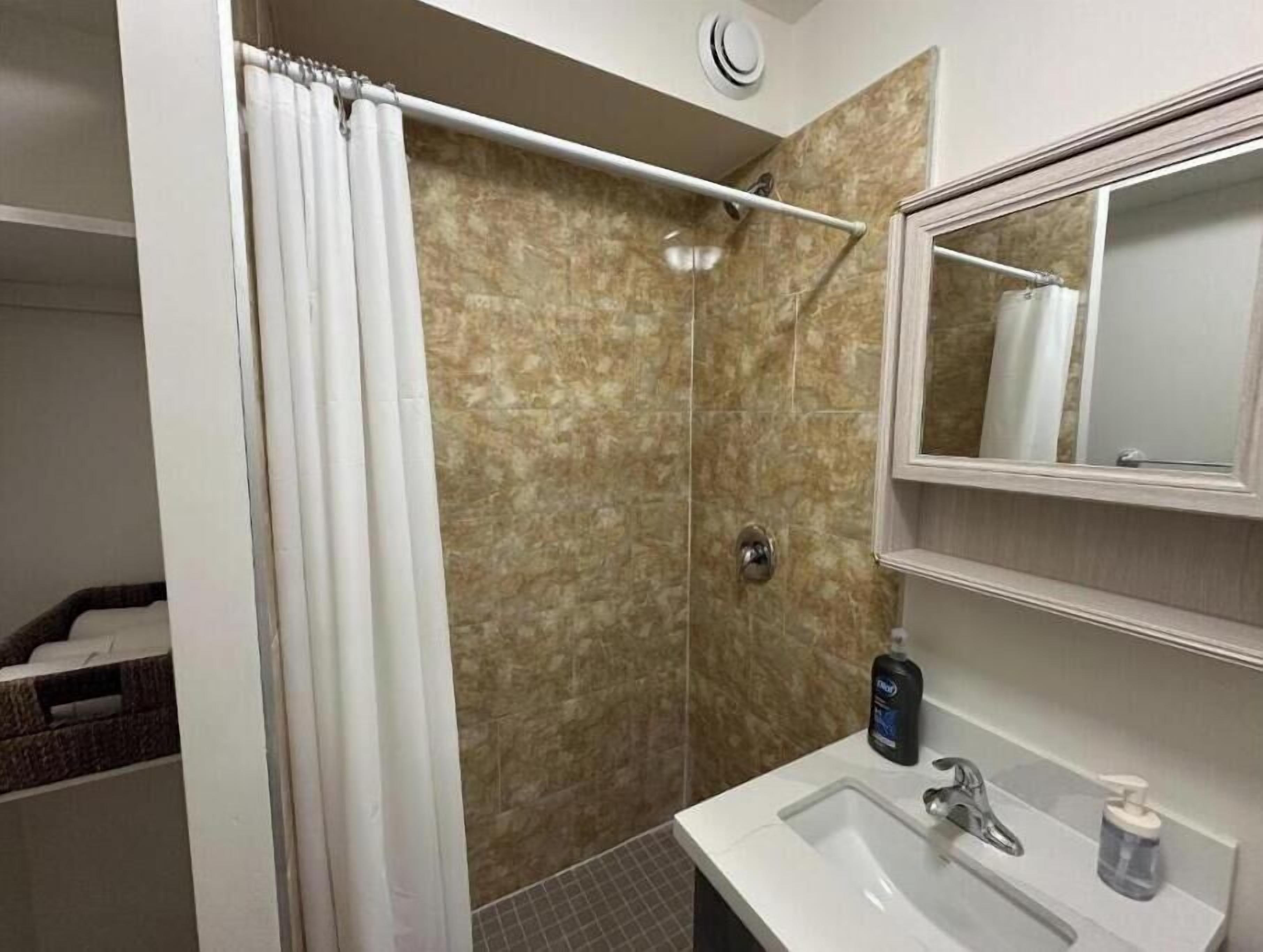 A bathroom with a shower, a sink, and a mirror.