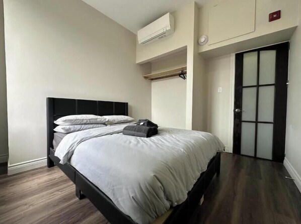Un dormitorio con cama, armario y aire acondicionado.