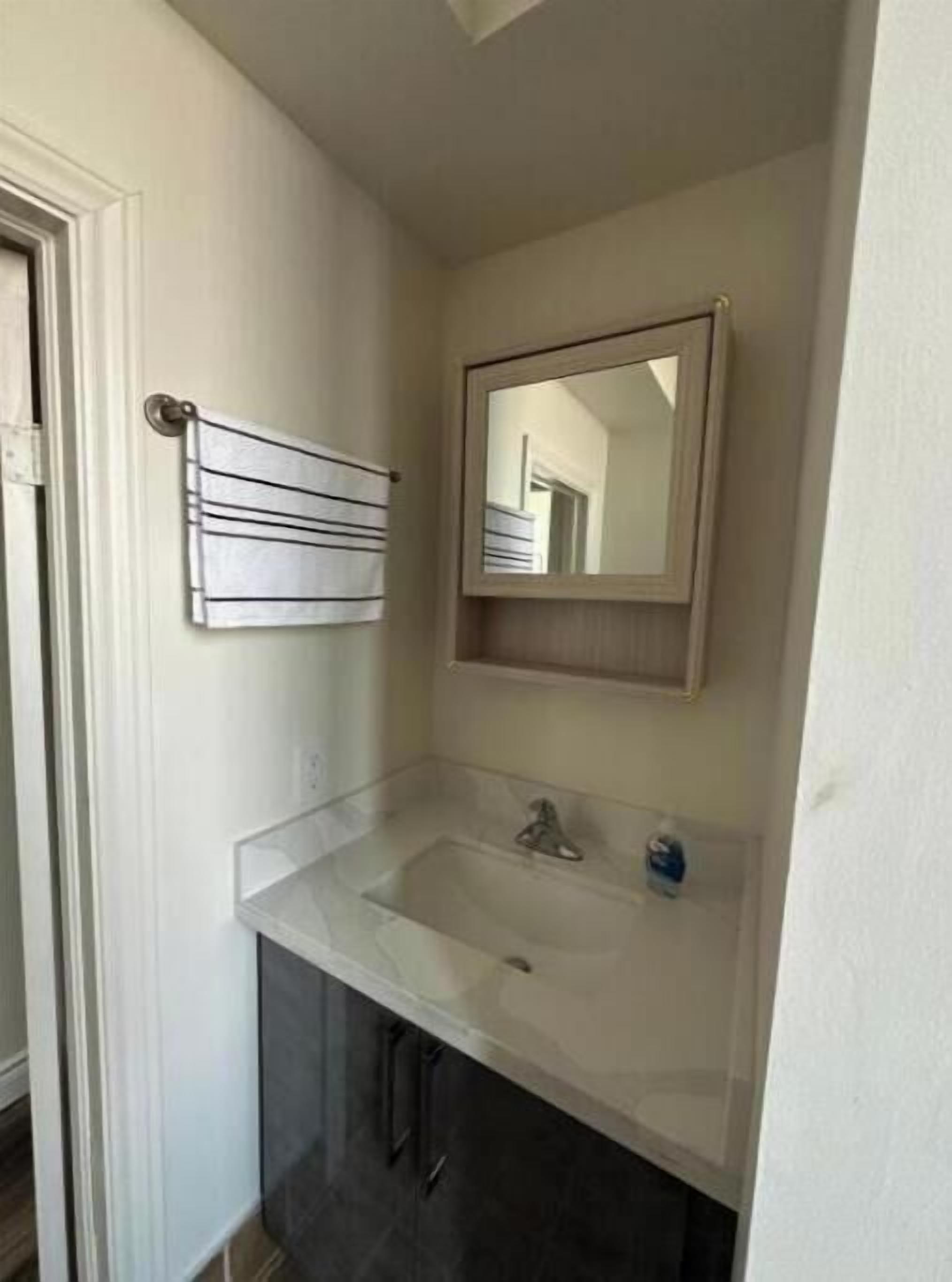 A bathroom with a white sink, a mirror, and a towel rack.