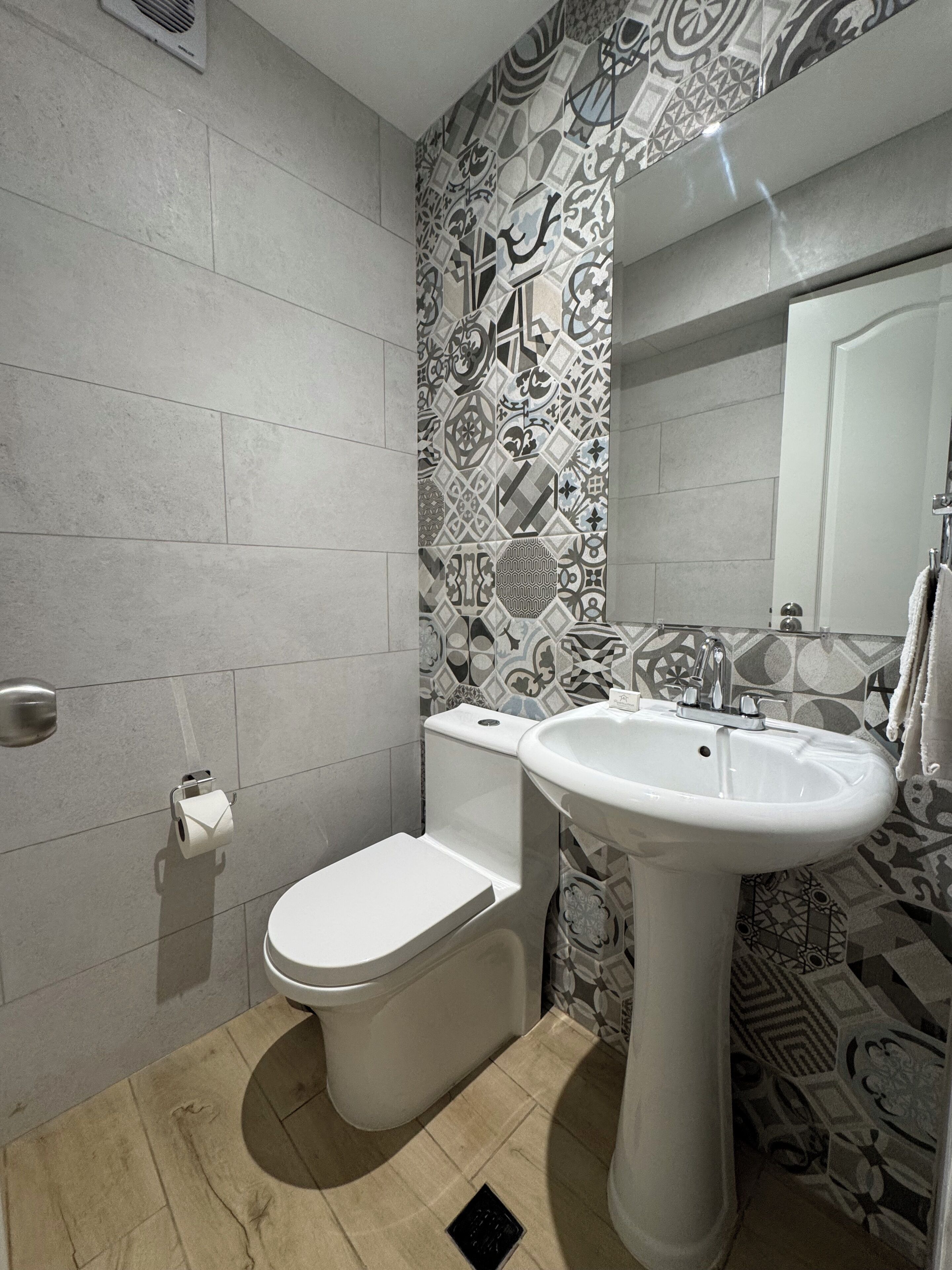 Ein modernes Badezimmer mit Toilette, Waschbecken und Wandfliesen mit Muster.