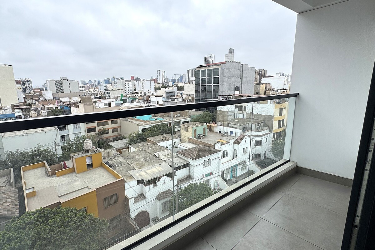 A balcony with a view of a cityscape, including buildings of various heights and architectural styles.
