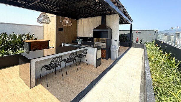 A rooftop bar with a wooden floor, black metal chairs, a bar counter, hanging lights, and a view of the city skyline. - Aparts4Days 1 Bedroom Apartment Miraflores 4255 (Lima)