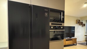 A modern kitchen with a black refrigerator, wooden cabinets, and a built-in oven. - Aparts4Days 1 Bedroom Apartment Miraflores 4255 (Lima)