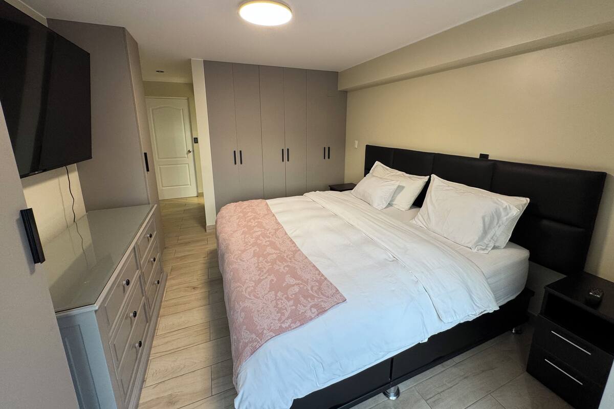 Un dormitorio con cama, cómoda, televisor y armario.