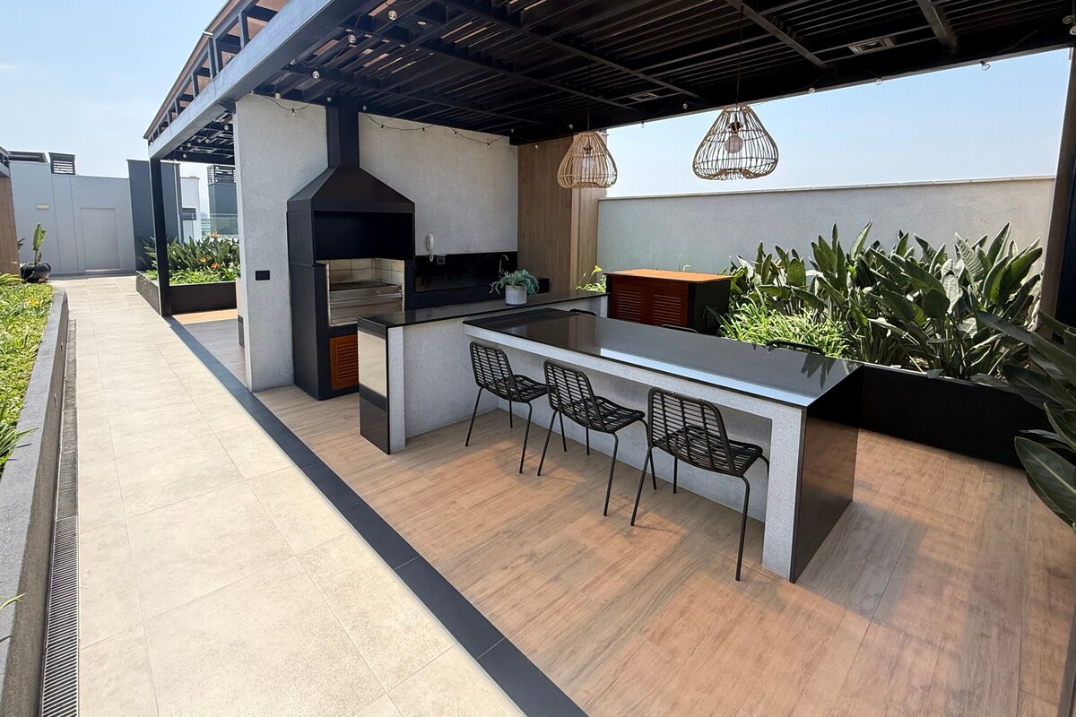 An outdoor kitchen area with a grill, bar counter, and seating.