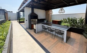 An outdoor kitchen area with a grill, bar counter, and seating. - Aparts4Days 1 Bedroom Apartment Miraflores 4255 (Lima)