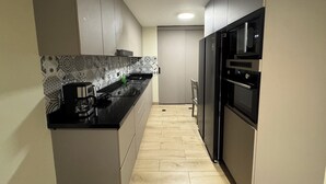 A modern kitchen with a black countertop, stainless steel appliances, and patterned backsplash. - Aparts4Days 1 Bedroom Apartment Miraflores 4255 (Lima)